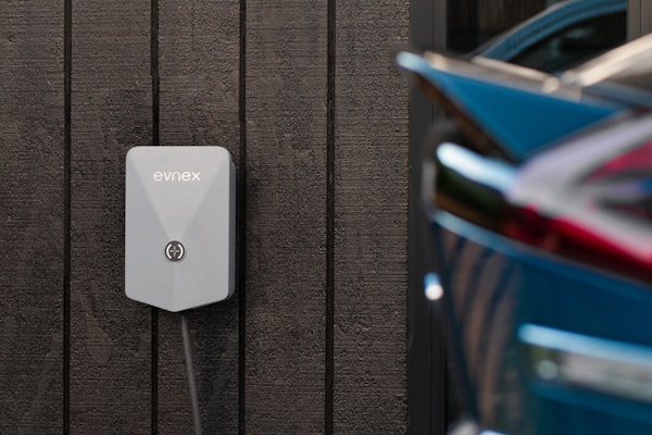 EV charging station mounted on garage wall with vehicle nearby